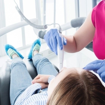 Pediatric dentist placing intraoral camera into child's mouth during dental checkup