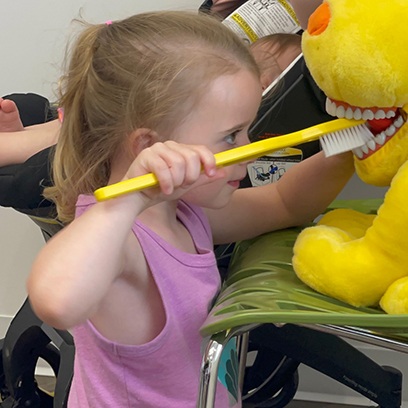 a child brushing the teeth of a stuffed animal