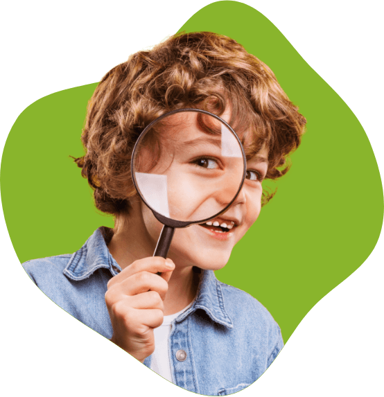 Smiling boy with magnifying glass in front of his eye