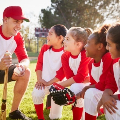 Man coaching a team of girls playing softball