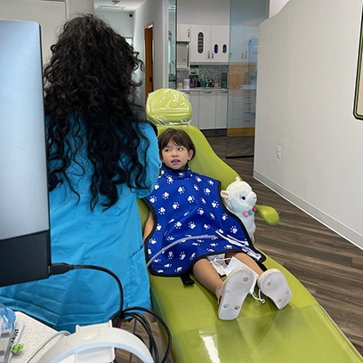 a dental assistant talking with a child sitting in a treatment chair