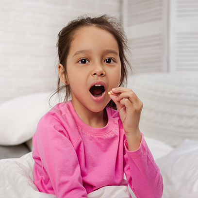 Young girl about to swallow a pill