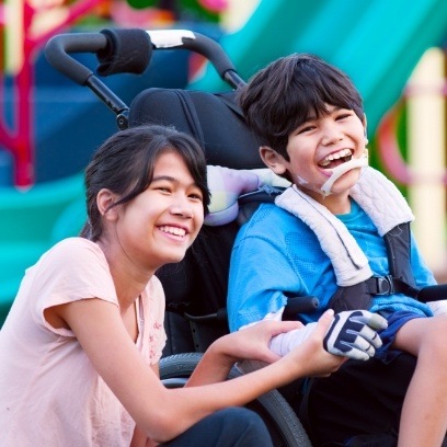 Young girl laughing with young boy in wheelchair after seeing pediatric special needs dentist in Leesburg