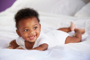 a smiling baby laying on a bed