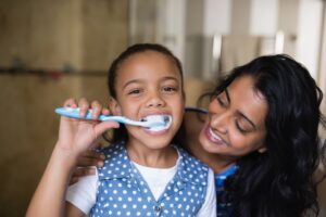 a mother watching her child brush her teeth