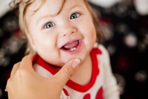 a smiling baby with her two front teeth