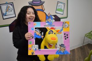 a dental assistant smiling and holding up a stuffed animal