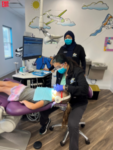 Dr. Takiar examining a child’s teeth while they lay back in a treatment chair