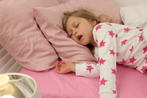 a snoring child sleeping in a bed